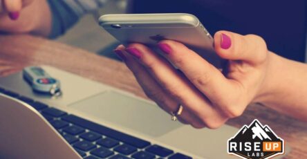 a girl holding a mobile and laptop